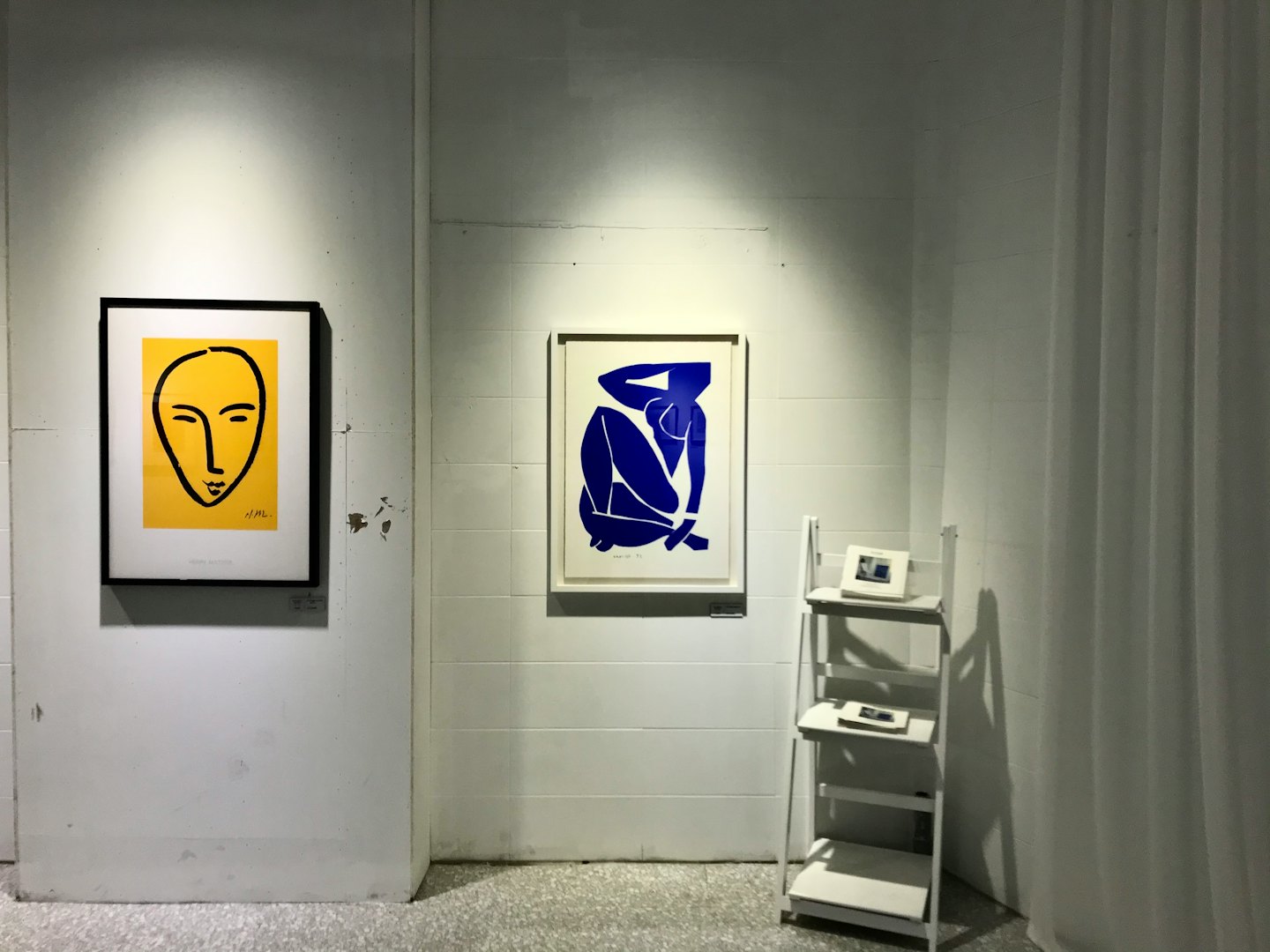 Two abstract art prints displayed on a white gallery wall.