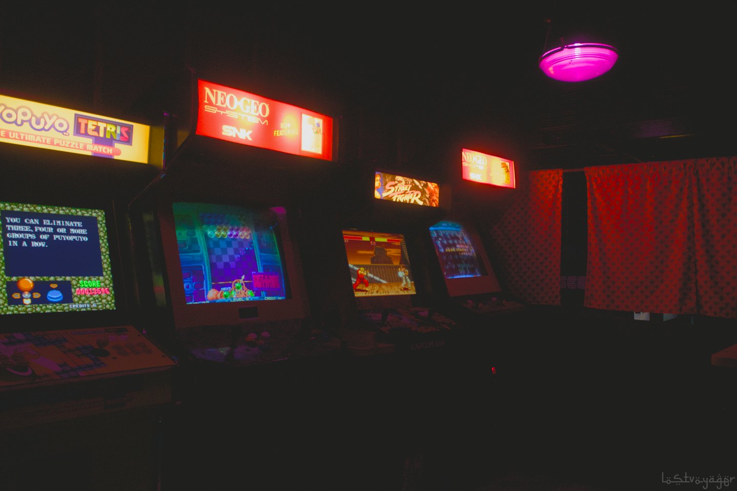 Glowing retro arcade cabinets line a dark gaming parlor.